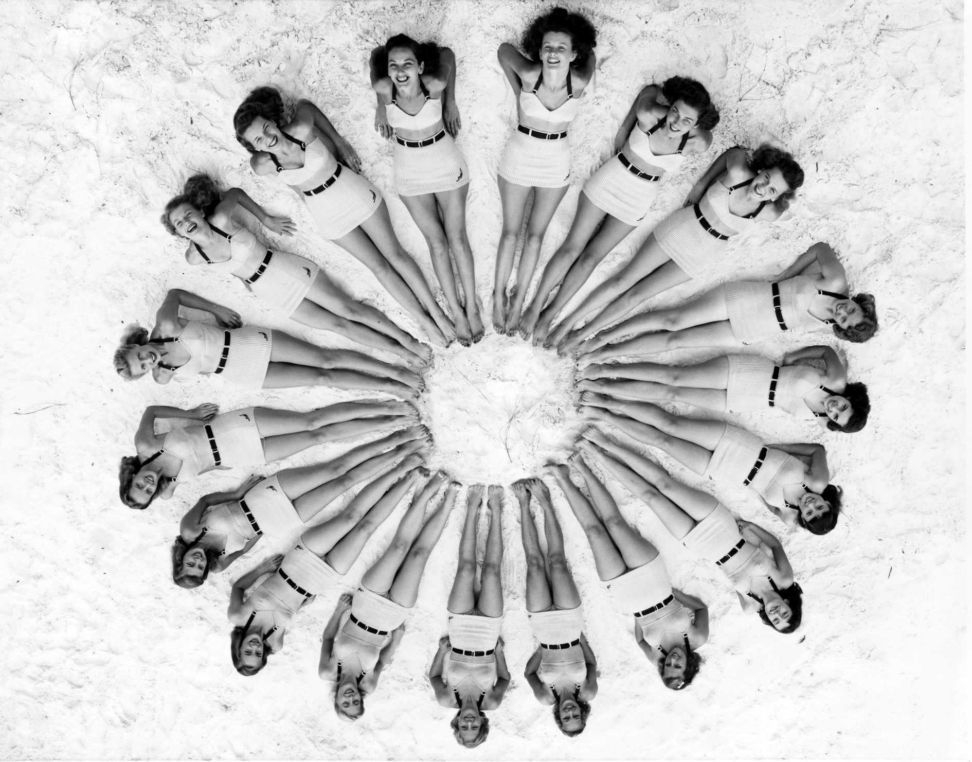 Women lying in circle around beach ball